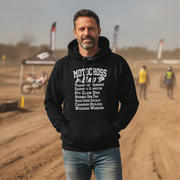Man wearing a black hoodie with 'Motocross Dad' text at a dirt track event.