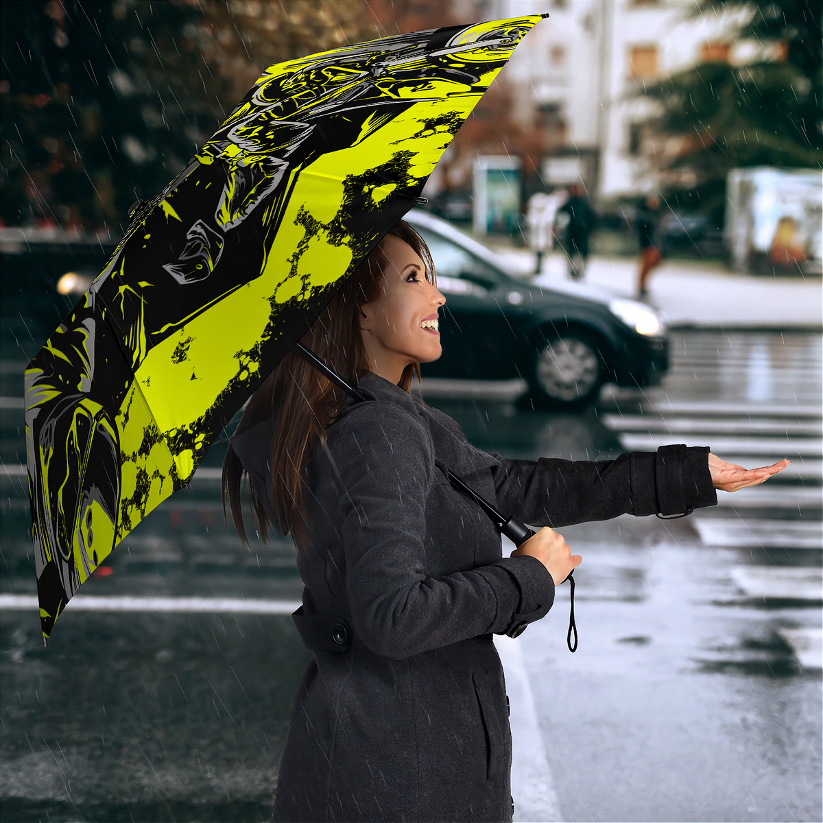 A woman in a dark gray coat stands in the rain on a city street holding a large open umbrella with a bold neon yellow and black abstract graphic print.
