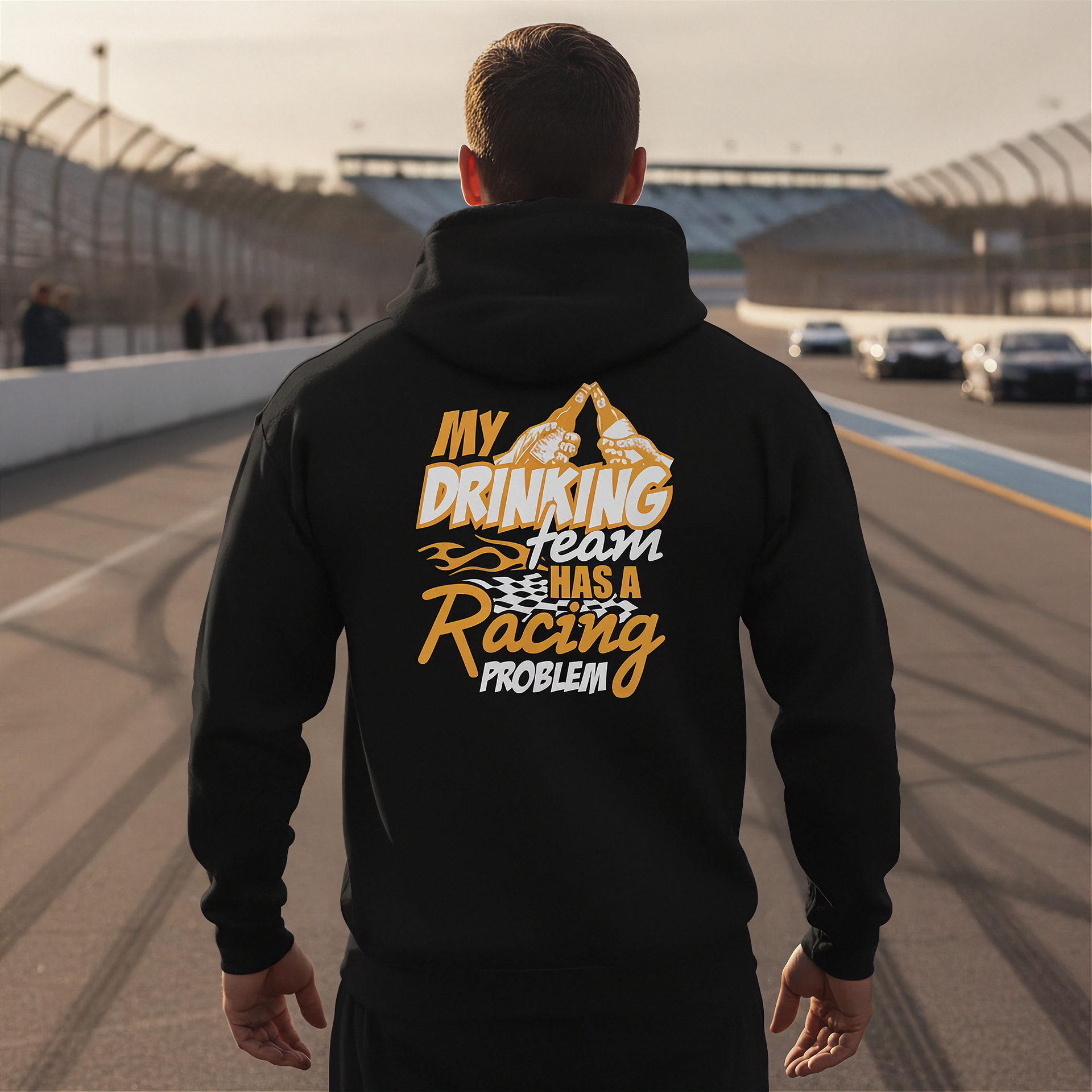 Man wearing a black hoodie with a humorous text design on a race track.