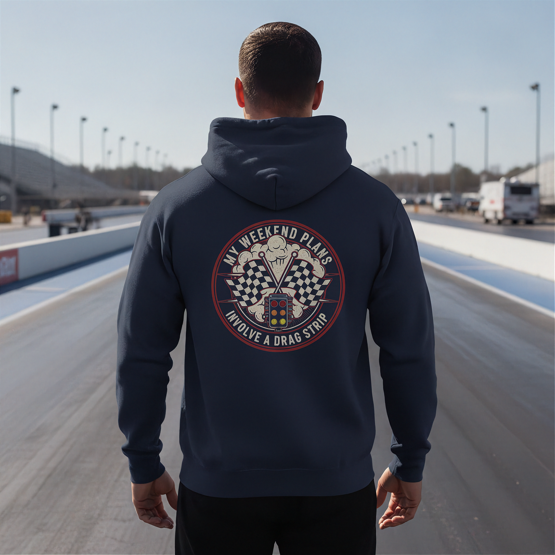 Man wearing a hoodie with a drag racing graphic on a racetrack