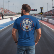 Man wearing a blue t-shirt with a graphic design on the back at a race track.