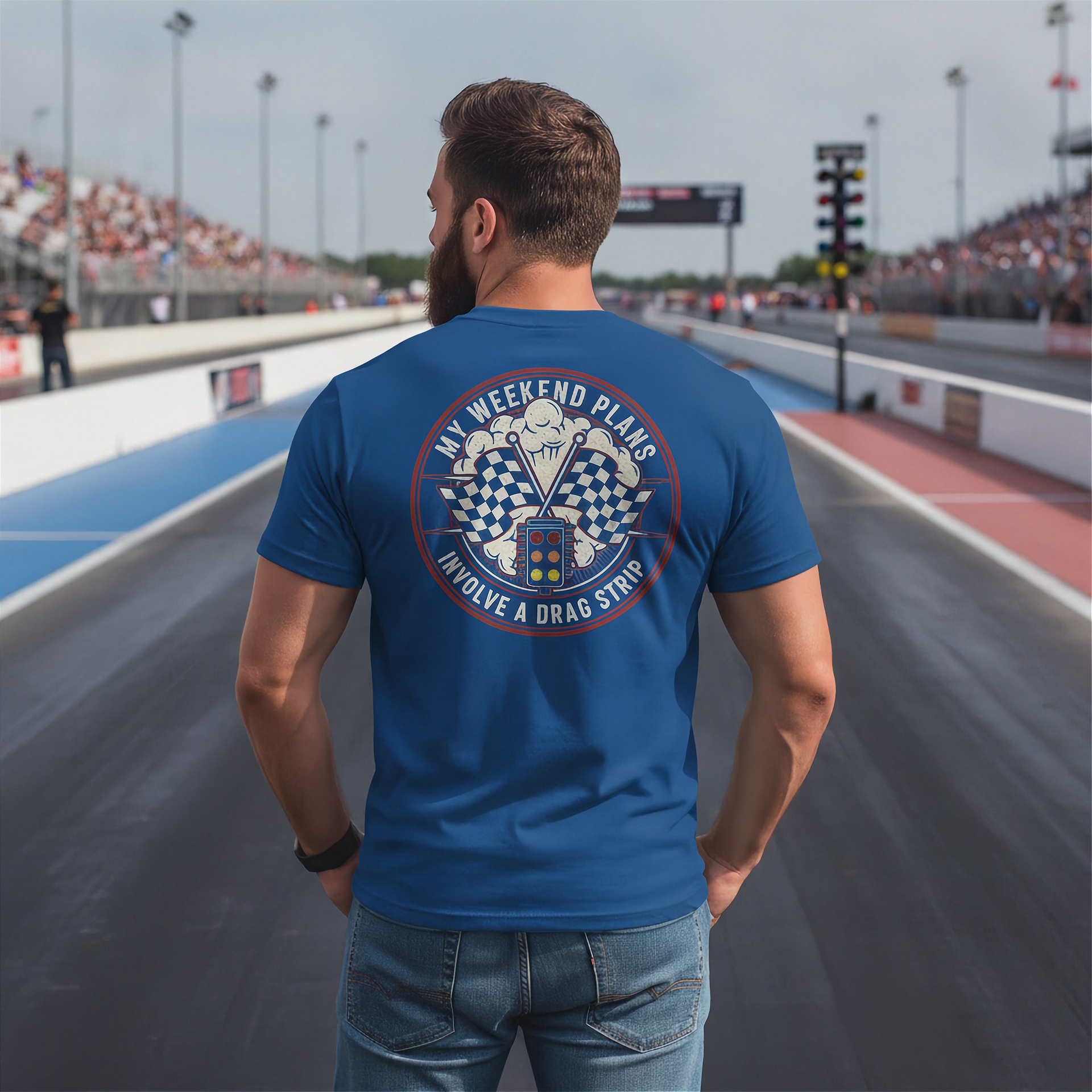 Man wearing a blue t-shirt with a graphic design on the back at a race track.