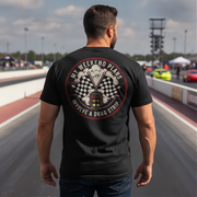 Man wearing a black t-shirt with a graphic design on the back at a race track.