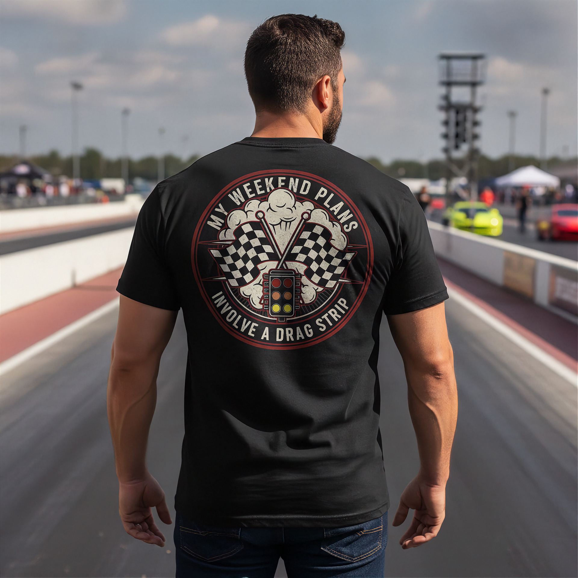 Man wearing a black t-shirt with a graphic design on the back at a race track.