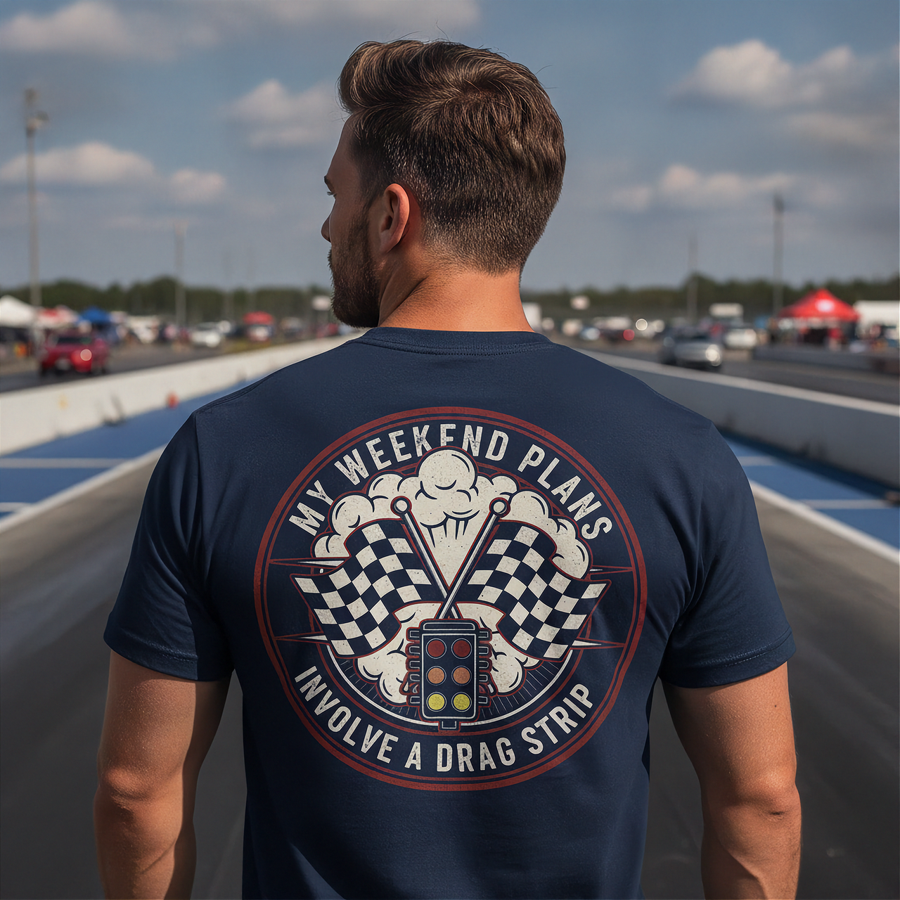 Man wearing a navy blue t-shirt with a drag racing graphic and text at a race track.