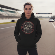 Woman wearing a black hoodie with a racing-themed design on a race track.