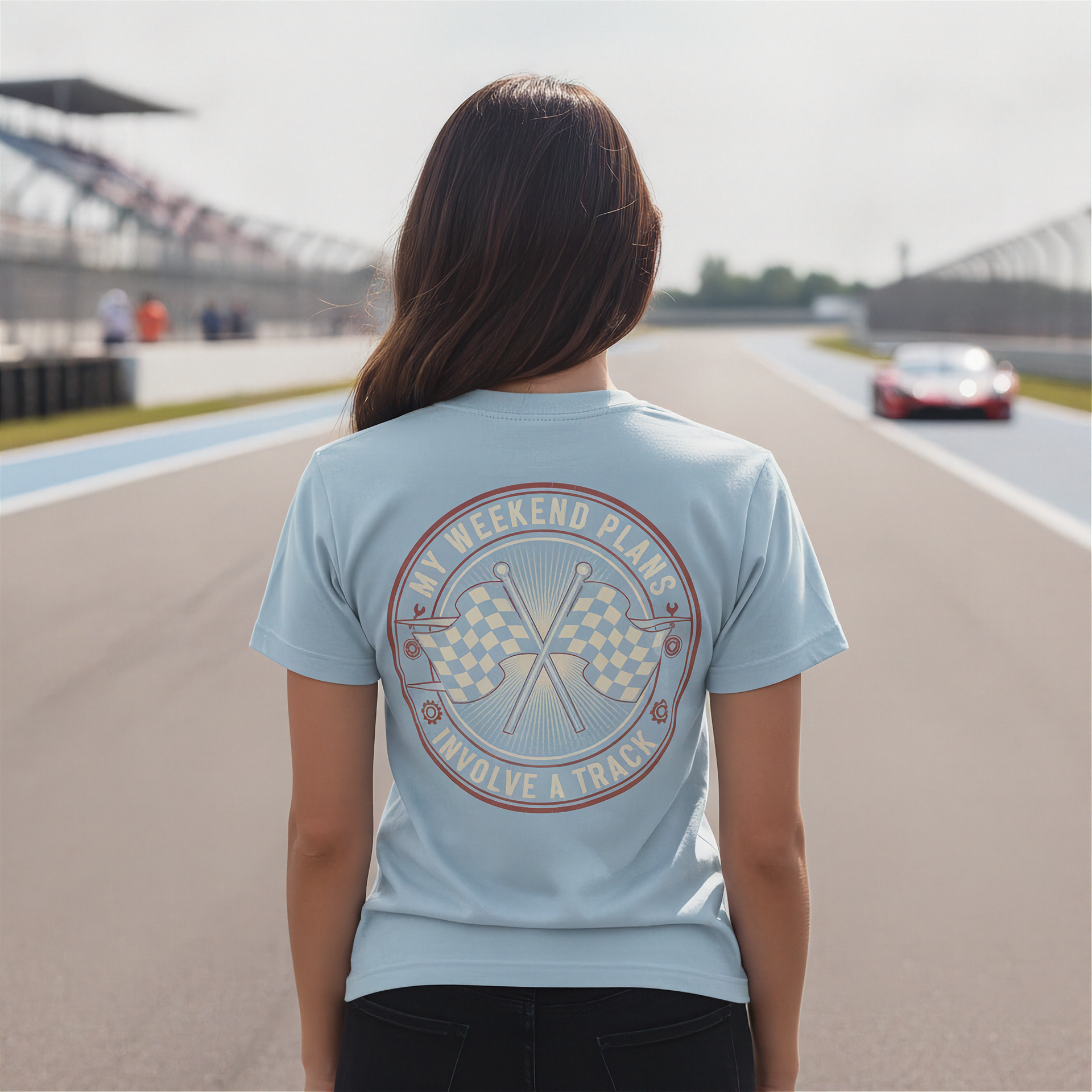 Woman wearing a light blue t-shirt with a track graphic and text on a race track background
