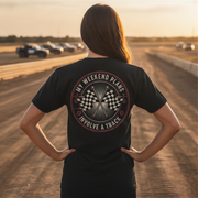 Person wearing a black t-shirt with a graphic design on a race track at sunset