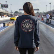 Woman wearing a sweatshirt with a track-themed design at a race track.