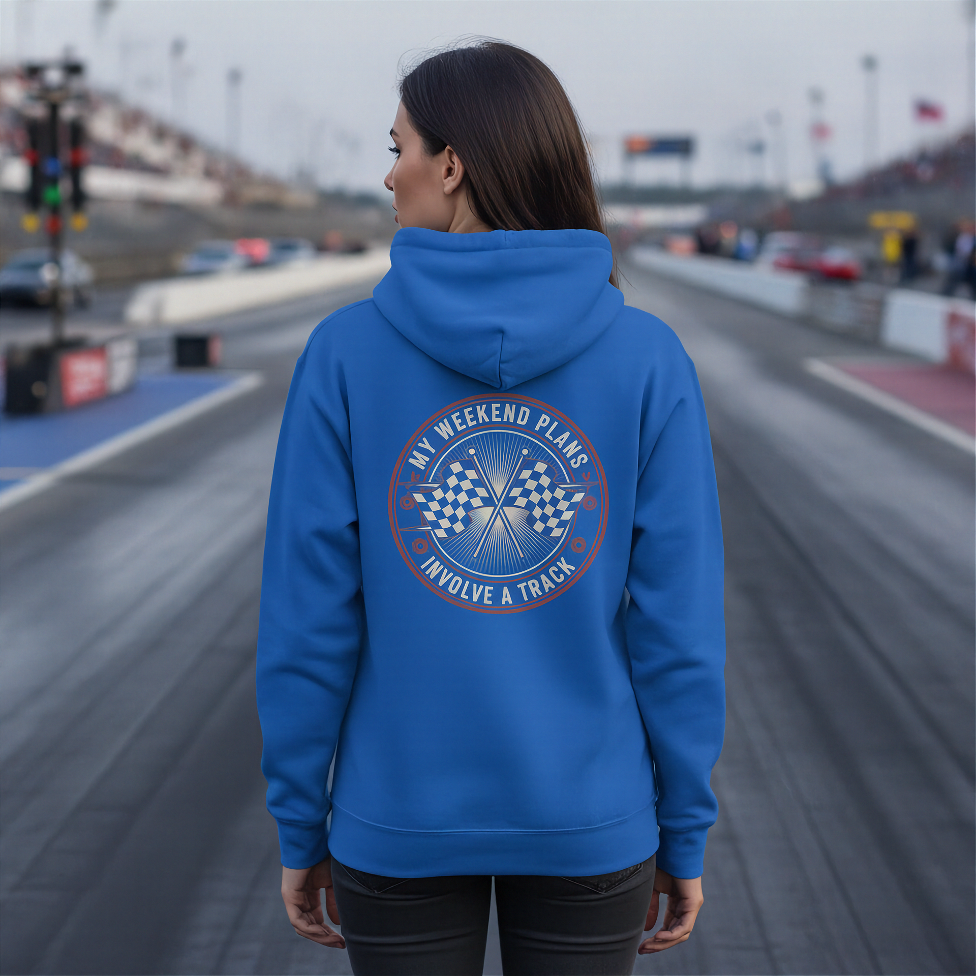 Man wearing a blue hoodie with a track-themed design on a race track background