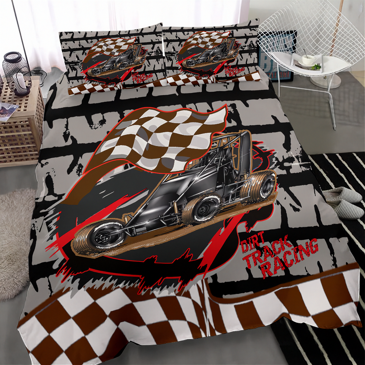 A bed made with a bold racing-themed bedding set featuring a black go-kart illustration, brown-and-white checkered flags, red brushstroke accents, and the words 'dirt Track Racing.' The room setting includes a chair, side table, rug, and window, so this is a Lifestyle image rather than a clean studio Product/Packaging shot.