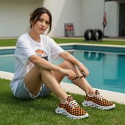 Woman sitting by a pool wearing checkered orange and black shoes.