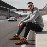 Man sitting on a race track wearing checkered shoes, gray hoodie, and black pants.
