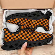 Orange and black checkered shoes in a box with a hand holding one shoe.