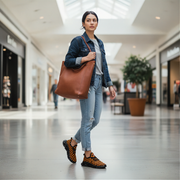 Woman walking in a mall holding a brown leather bag and wearing orange checkered shoes