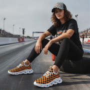 Woman wearing black and orange checkered sneakers sitting on a race track.