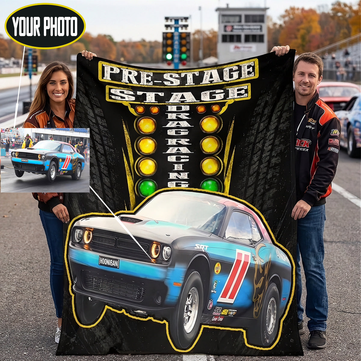 A custom drag racing themed blanket held up by a man and a woman on an outdoor racetrack. The blanket features a black background with a tire tread pattern, a yellow and black 'PRE-STAGE DRAG RACING' sign, and a blue, black, and red Dodge Challenger race car graphic.