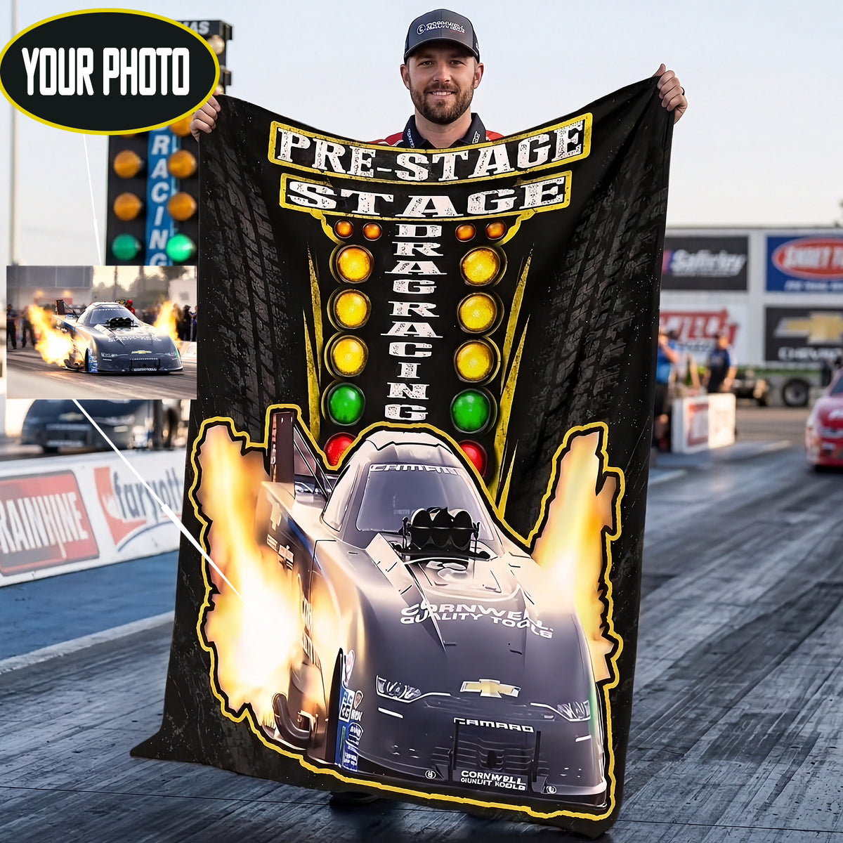A man wearing a baseball cap holds up a large black drag racing themed blanket or poster in an outdoor drag strip setting. The design features a black race car with flames, a vertical column of yellow, green, and red lights, and the words 'PRE-STAGE' and 'DRAG RACING'.