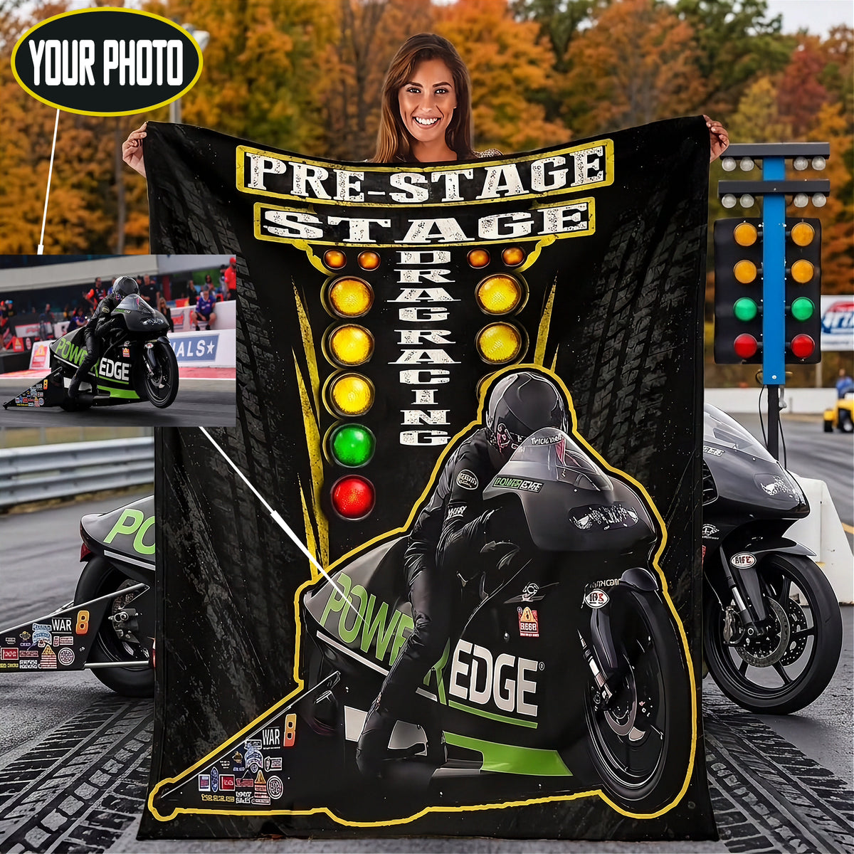 A woman holds up a large black blanket or throw featuring a motorcycle racer on a track, with the words 'PRE-STAGE DRAG RACING' and a yellow-green checkered light graphic. The background shows a racetrack scene with motorcycles and a traffic light, plus a small inset photo of a woman's photo frame.