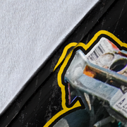 Close-up of a black surface with a yellow and black outlined graphic sticker partially peeled back, revealing a textured white layer underneath.