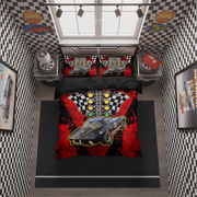 A top-down bedroom scene showing a racing-themed bedding set on a bed. The duvet cover and two matching pillowcases feature a black race car graphic, checkered flags, and red splatter details.