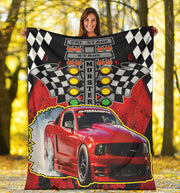 Woman holding a personalized drag racing blanket with a red Mustang, Christmas tree starting lights, and sample name MONSTER in an autumn setting.