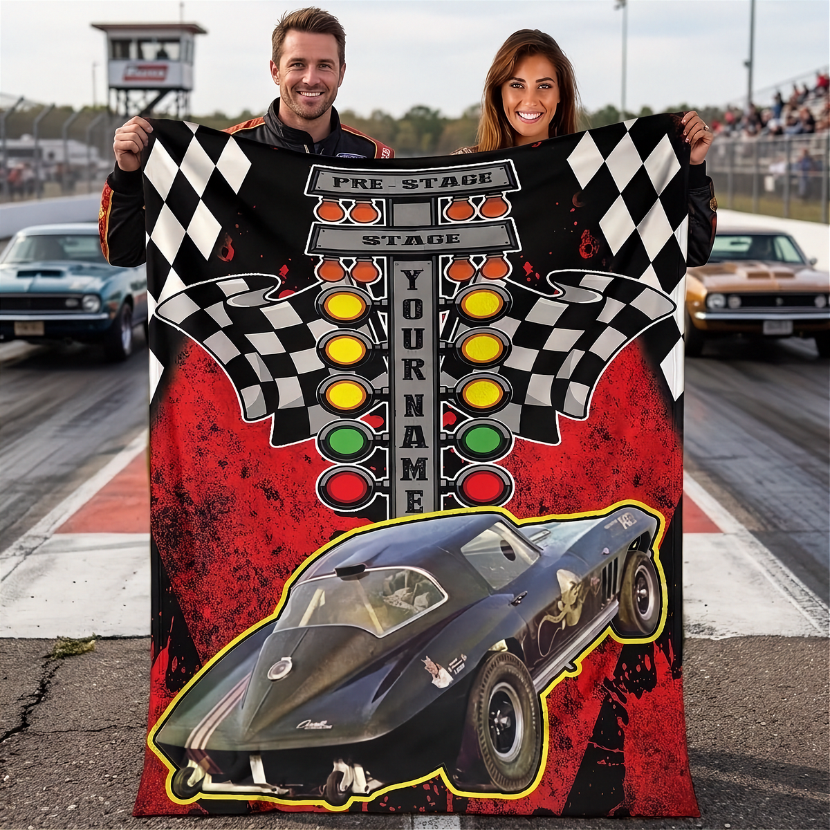 Couple displaying a red-and-black drag racing blanket with a black race car photo, starting-light tree and sample YOUR NAME text.