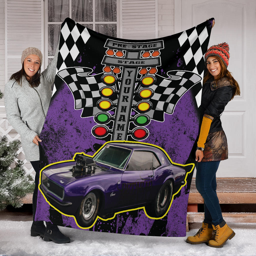 Two people holding a blanket with a car and race track design.