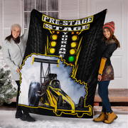 Two people holding up a custom fleece blanket featuring a drag racer graphic and 'PRE-STAGE STAGE YOUR NAME' text, set against a snowy porch background.