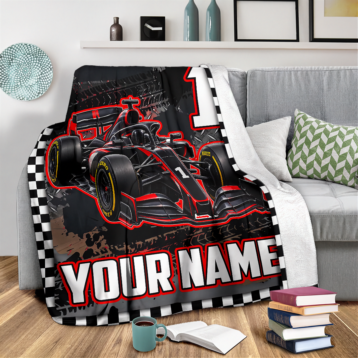 A fleece throw blanket featuring a red and black Formula 1 race car with a large number 1, set against a checkered border and the customizable text 'YOUR NAME'. The blanket is shown draped over a gray sofa in a living room setting.