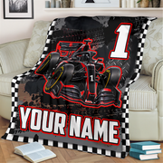 A custom racing-themed blanket draped over a light beige sofa in a living room setting. The blanket features a black and red Formula 1 style race car graphic, a large white number '1', a black and white checkered border, and customizable text reading 'YOUR NAME'.