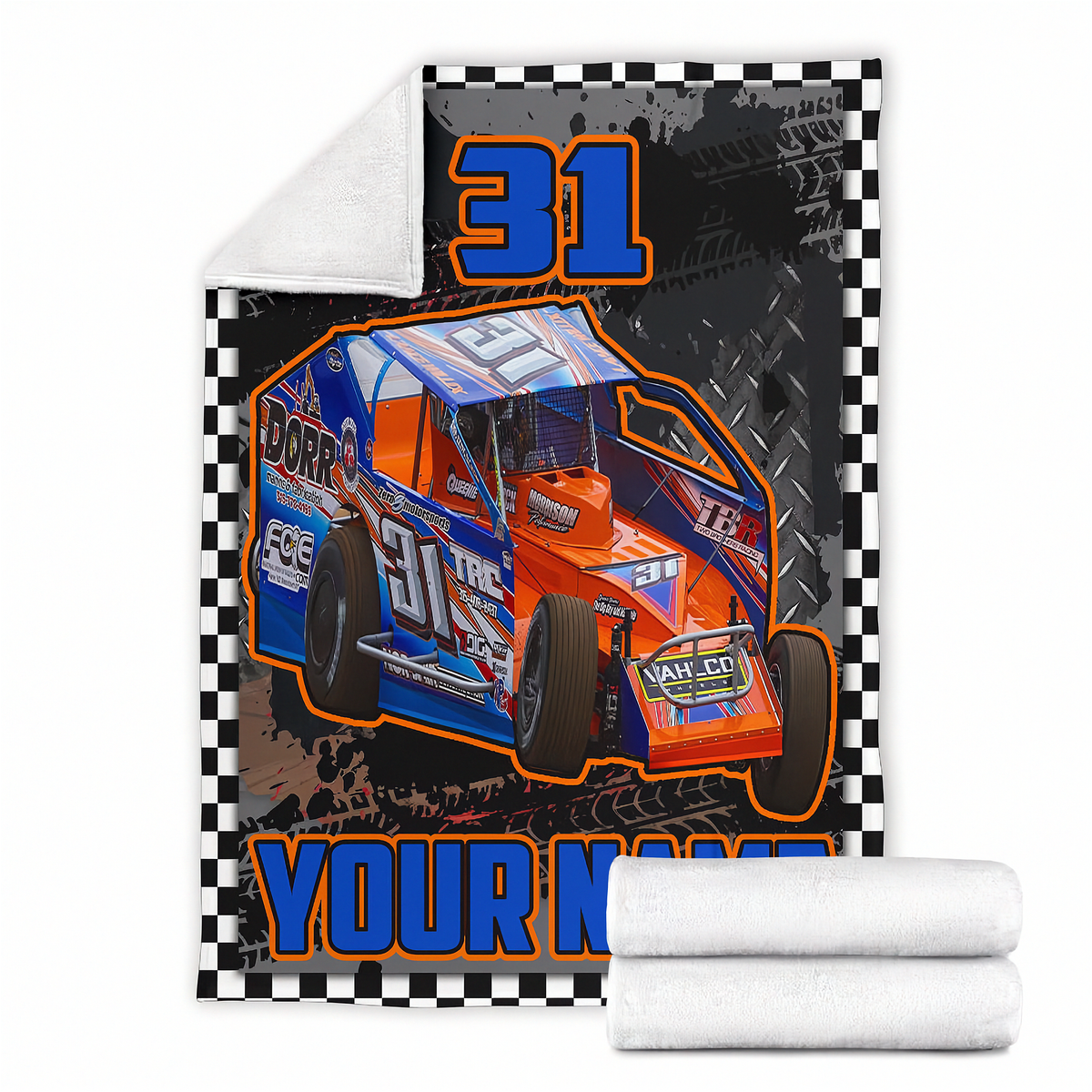 A custom printed fleece blanket featuring a blue and orange race car with the number 31, a black-and-white checkered border, and a white sherpa lining. Two rolled white towels are shown in front of the blanket on a plain white background.