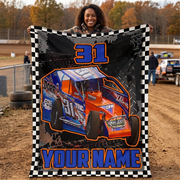 A person outdoors holds up a large custom race car blanket featuring a blue and orange sprint car, the number 31, tire tracks, and the text 'YOUR NAME'.