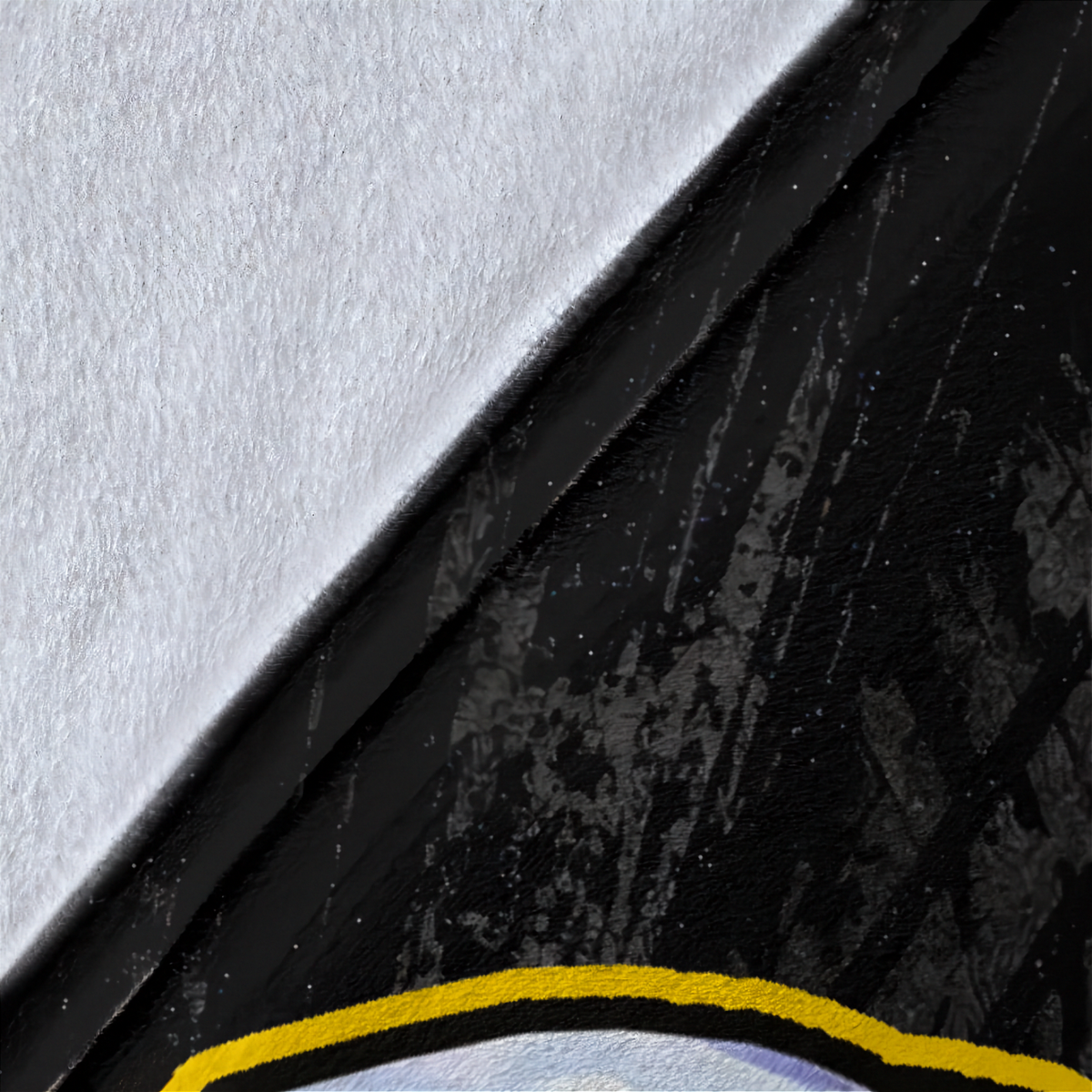 A close-up detail shot of a product showing a diagonal split between a textured white surface and a black distressed surface with a yellow curved accent line at the bottom.