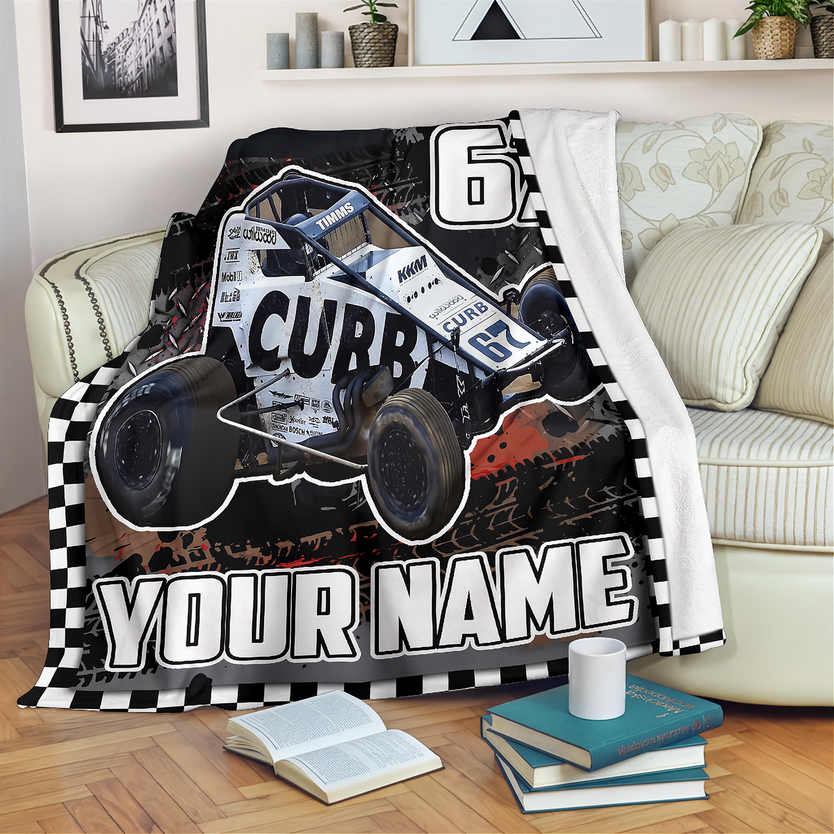 A personalized racing blanket draped over a sofa in a living room setting. The blanket features a black and white checkered border, a graphic of a white and blue Non Wing race car with 'CUBB' and number '62' printed on it, and the text 'YOUR NAME' in bold white letters.