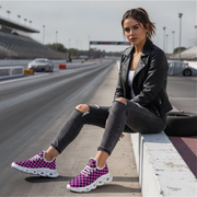 Woman sitting on a race track wearing black leather jacket, ripped jeans, and pink checkered sneakers.