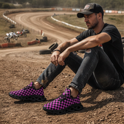 Man sitting on a dirt track wearing black and pink checkered shoes