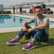 Man sitting by a pool wearing purple checkered shoes with a race track in the background