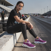 Woman sitting on a race track wearing checkered sneakers