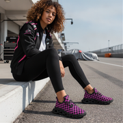 Woman sitting on a track wearing black and pink checkered shoes