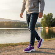 Person wearing purple checkered sneakers walking by a lake with mountains in the background