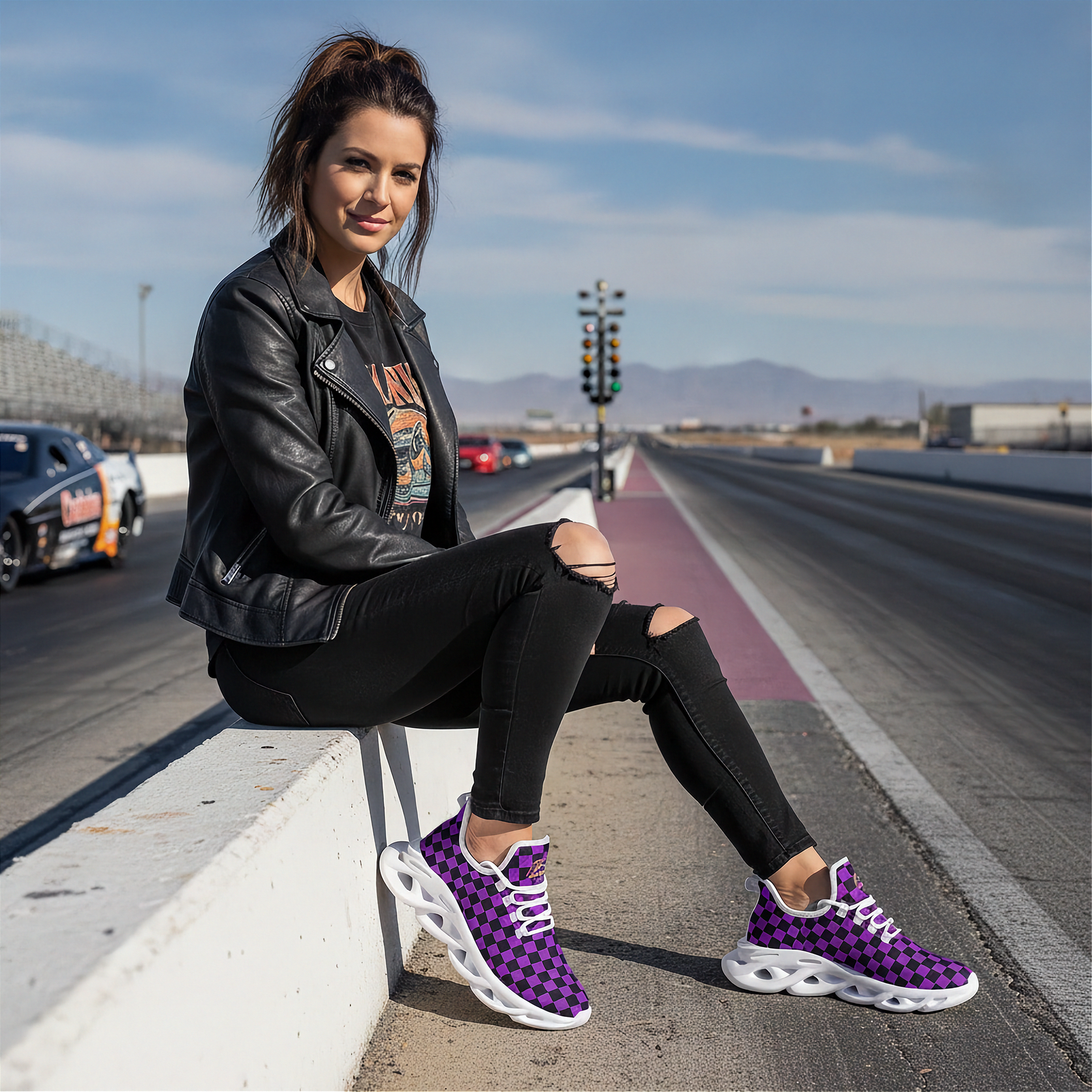 Woman sitting on a track wearing black leather jacket, black pants, and purple checkered sneakers.