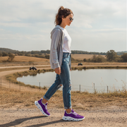 Woman walking on a dirt path near a pond with a scenic background