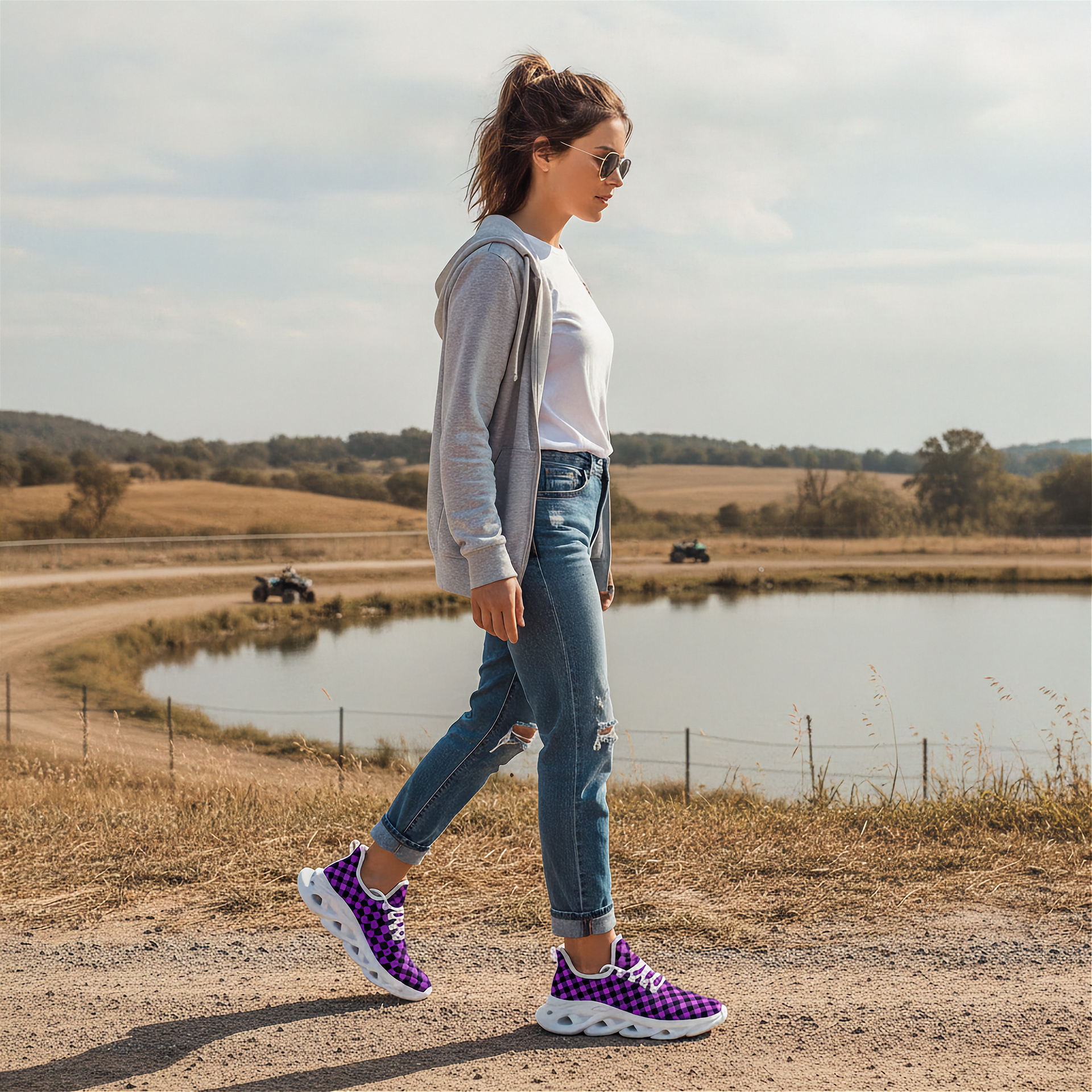 Woman walking on a dirt path near a pond with a scenic background