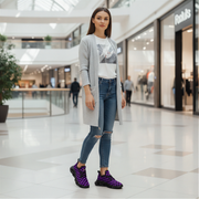 Woman in a gray cardigan and ripped jeans and purple checkered shoes standing in a shopping mall.