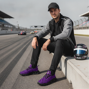 Man sitting on a race track with racing shoes and helmet
