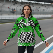 A woman stands on a racetrack wearing a bright green hoodie , featuring a large 'Racing' graphic with checkered flags and white tire tracks.
