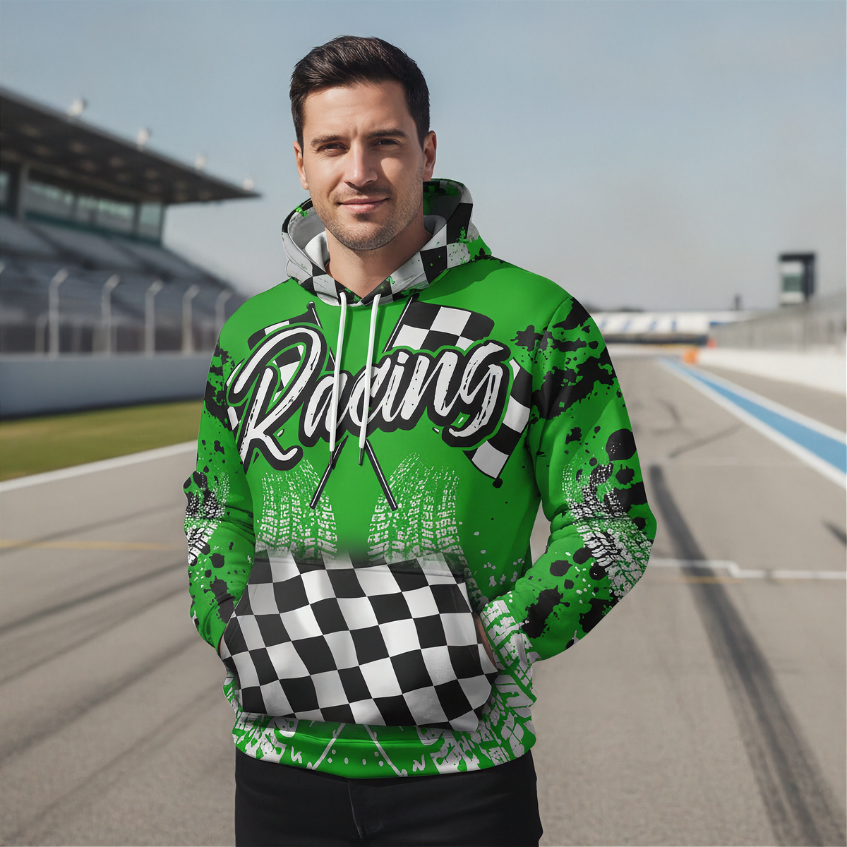 A man wearing a green and black checkered hoodie with 'Racing' printed across the chest, standing on a racetrack.