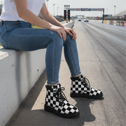 Woman wearing black and white checkered boots sitting on a race track.