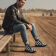 Man sitting on a bench wearing checkered boots with a dirt track and riders in the background.